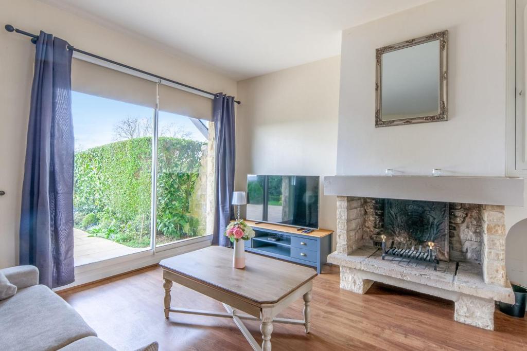 ein Wohnzimmer mit einem Kamin und einem großen Fenster in der Unterkunft Nice flat in a beautiful estate 15 min by walk from Deauville - Welkeys in Tourgéville