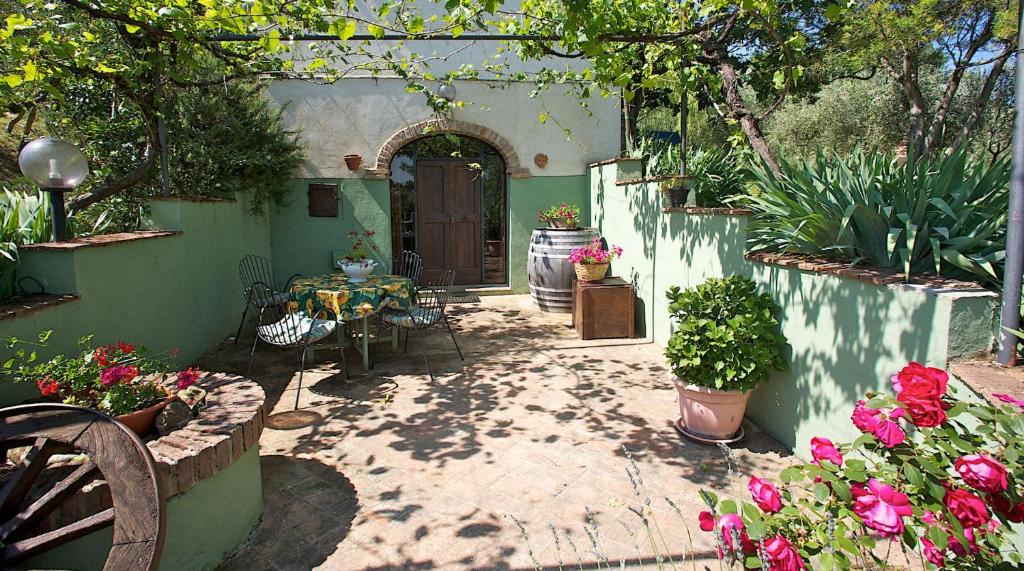 un patio al aire libre con mesa, sillas y flores en Fonte del Salcio, en Cinigiano