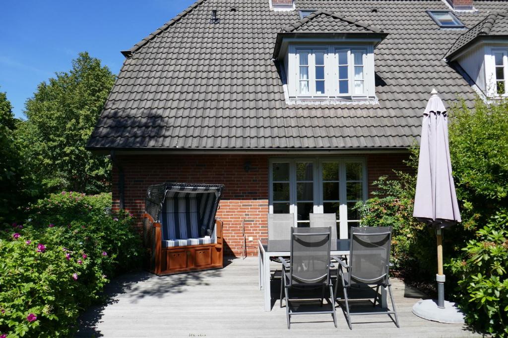 un patio con una mesa y una sombrilla y una casa en Haus Sommerfrische, en Südstrand