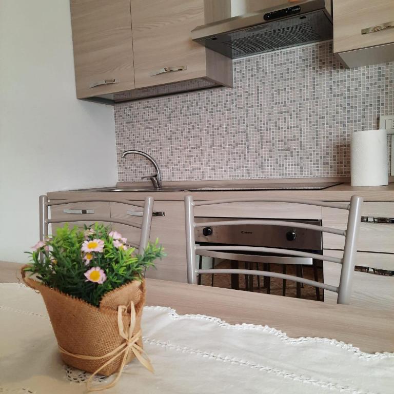 - une cuisine avec une table et une corbeille de fleurs dans l'établissement Appartamento Legnone - Your Mountain Holiday, à Tremenico
