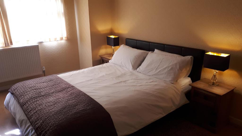 um quarto com uma cama com lençóis brancos e almofadas em Picturesque area cosy beds Netflix em Chester