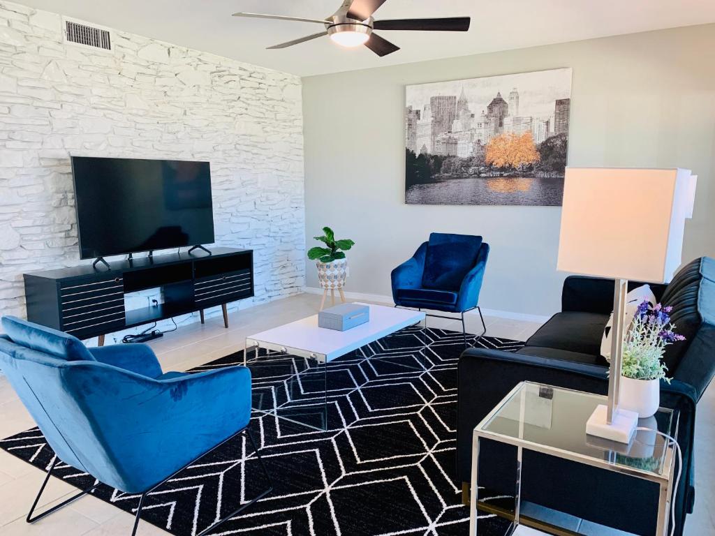 a living room with blue chairs and a flat screen tv at Blue-Door RESIDENCE @Maywood in San Antonio