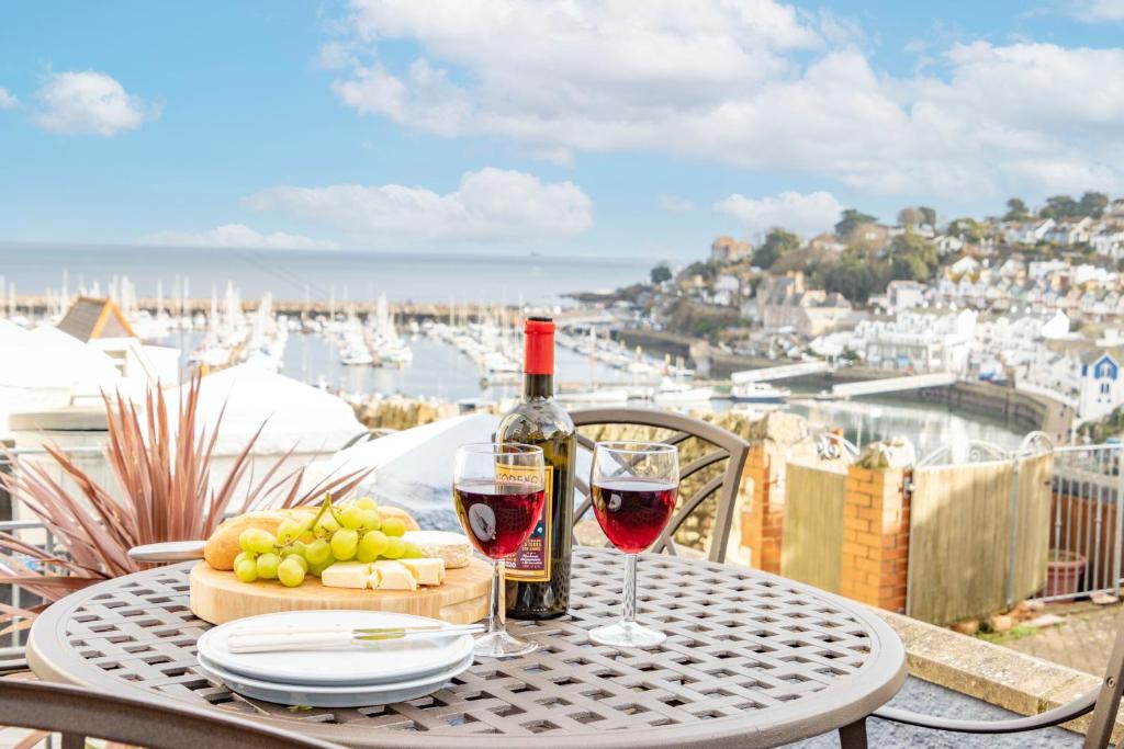 a table with a bottle of wine and wine glasses at Dolphin Cottage in Brixham