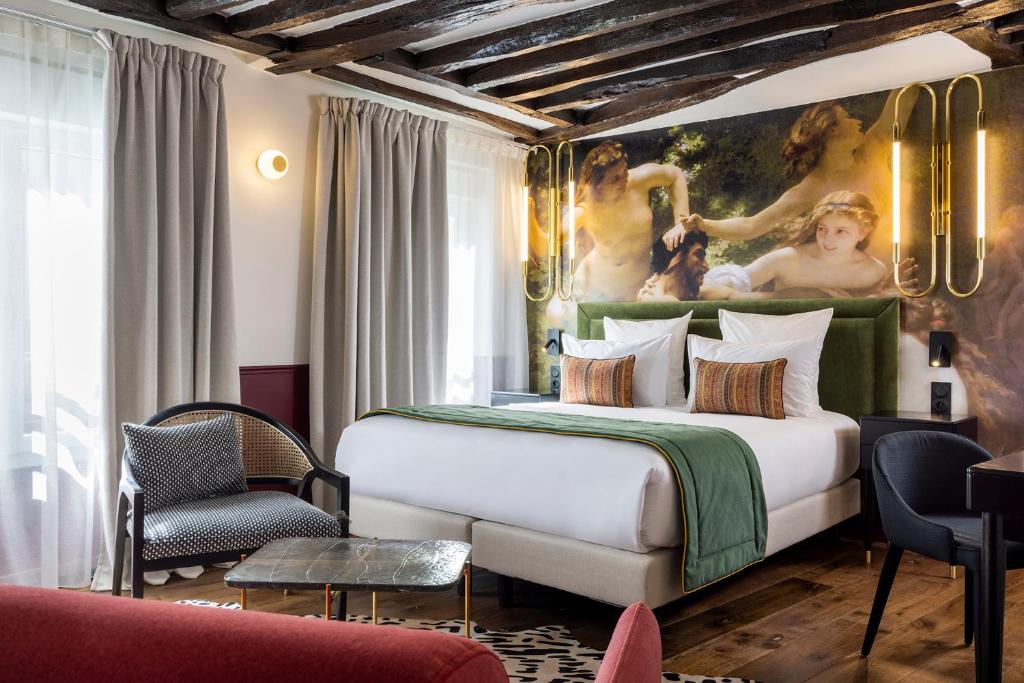 a bedroom with a large bed with a painting on the wall at Hotel Louis II in Paris