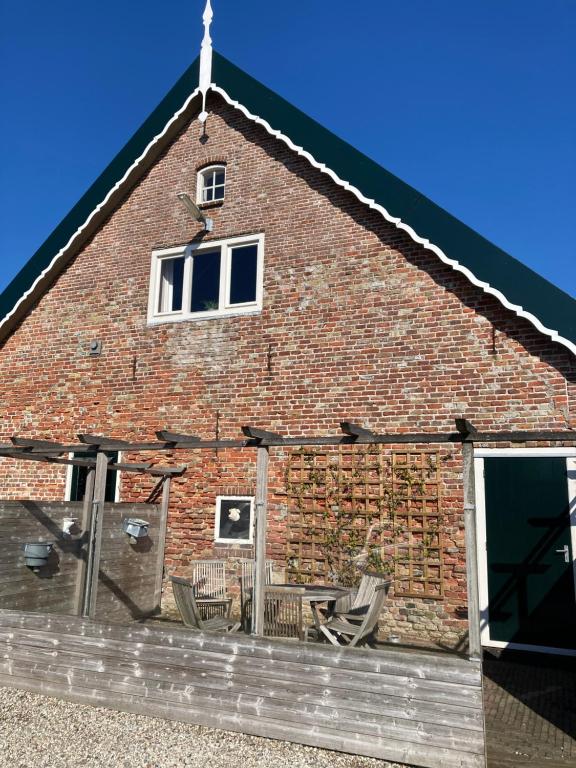 un edificio de ladrillo con 2 ventanas y 2 sillas en Van Zweeden Verhuur, en Biggekerke