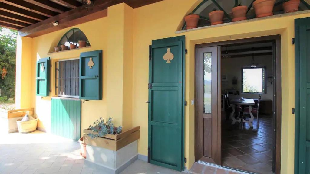 una casa con una puerta verde y una mesa en Casa in campagna oltrepo' pavese en Montecalvo Versiggia