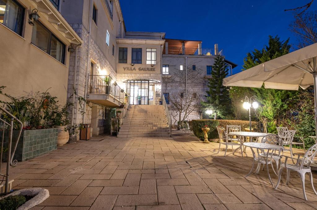 eine Terrasse mit Tischen und Stühlen vor einem Gebäude in der Unterkunft Villa Galilee Boutique Hotel and Spa in Safed