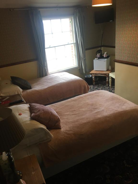 two beds in a hotel room with a window at Regency House in Walton-on-the-Naze