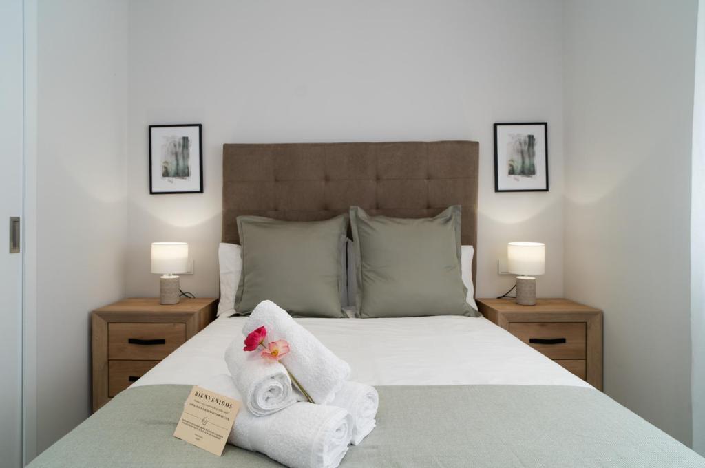 1 dormitorio con 1 cama con toallas y 2 lámparas en AAC Málaga - Apartamento muy cómodo y bien comunicado, a 1,3km del centro en Málaga