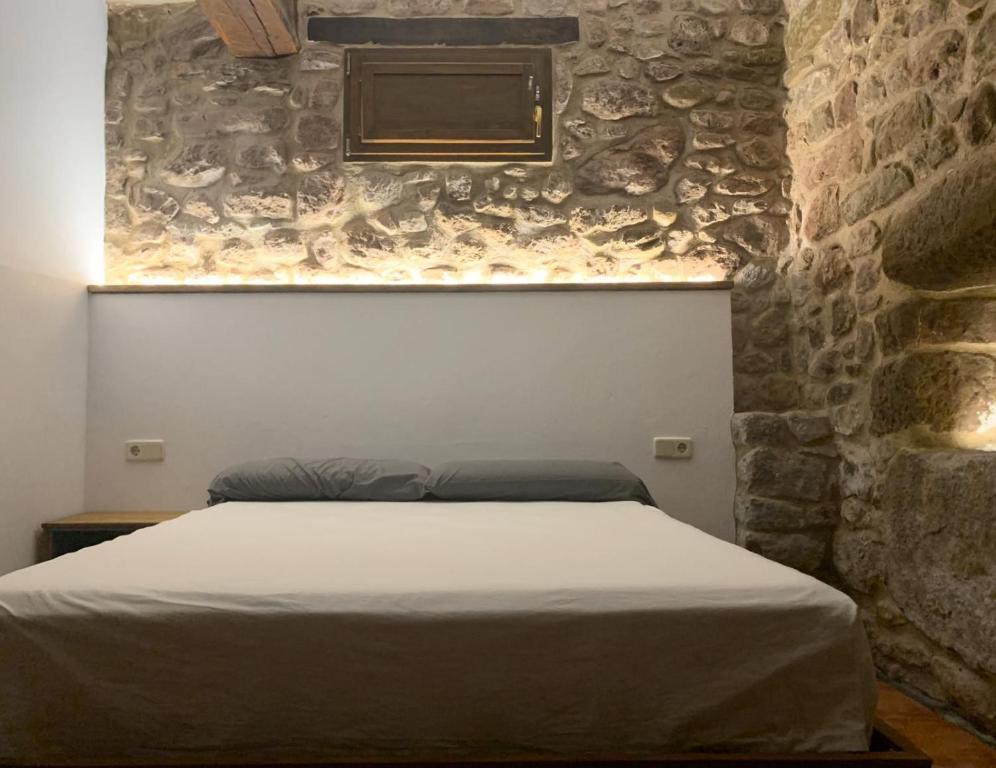 Cama en habitación con pared de piedra en CAN VOLAN, en Sant Pere Despuig