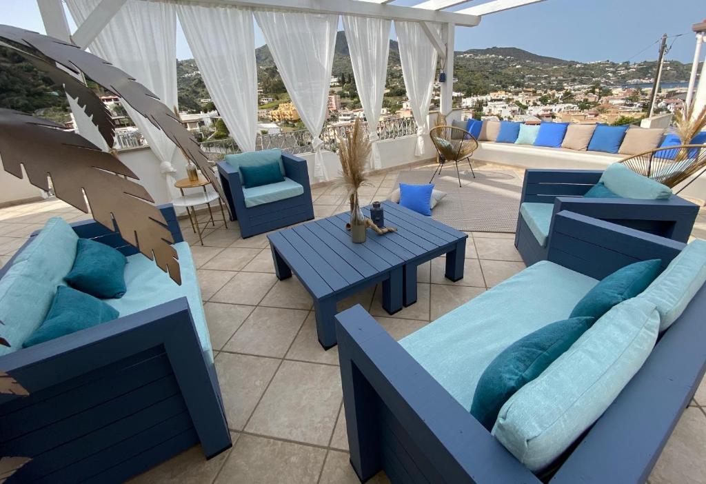 un patio con sillas azules y mesas en el techo en TaliaKà B & B, en Lipari