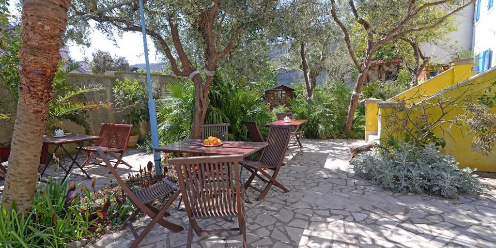 un patio con mesas y sillas en un jardín en Pjacal en Veli Lošinj