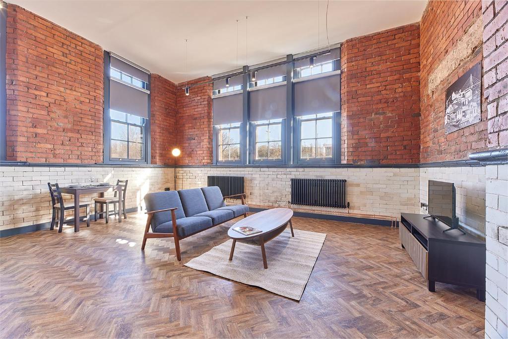 a living room with a couch and a table and a fireplace at No 3 at Simpson Street Apartments Sunderland in Sunderland