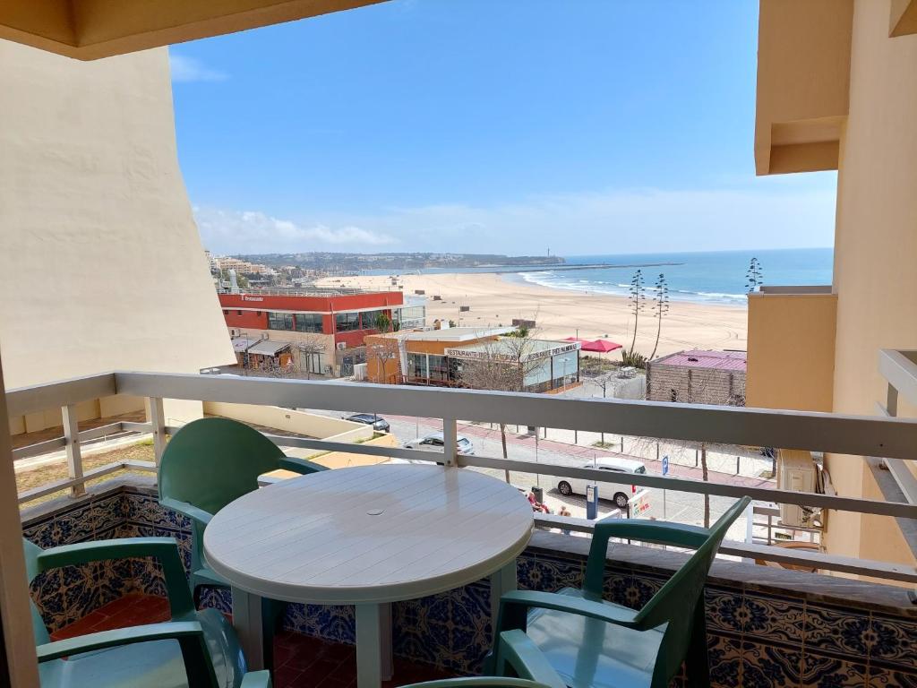 einen Balkon mit einem Tisch und Stühlen sowie einem Strand in der Unterkunft Alltravel Atlântico apartment in Portimão
