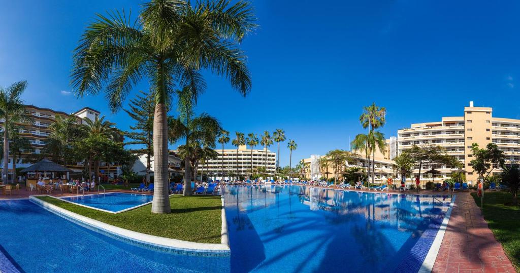 une grande piscine avec des palmiers et des bâtiments dans l'établissement Complejo Blue Sea Puerto Resort compuesto por Hotel Canarife y Bonanza Palace, à Puerto de la Cruz