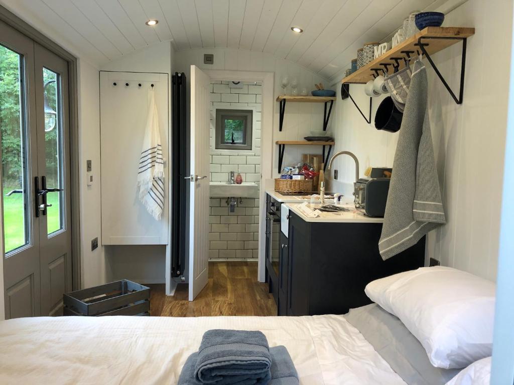 a bedroom with a bed and a kitchen with a sink at Luxury Shepherds Hut - The Sweet Pea by the lake in York