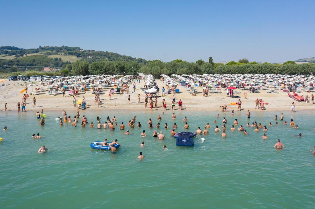 a large group of people in the water at a beach at Centro Vacanze Camping Spinnaker in Marina Palmense