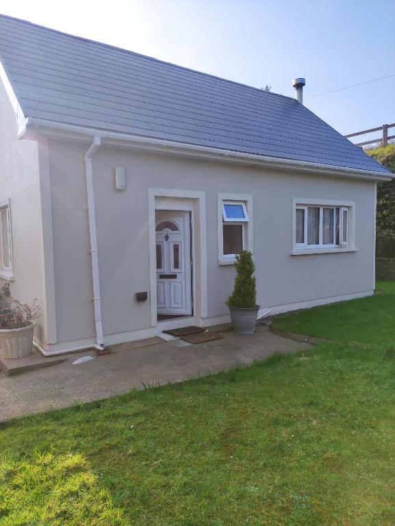 a white house with a door and a yard at Miriam's Cottage West Cork in Drom dhá Liag