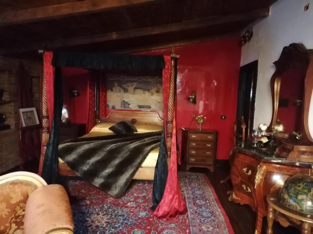 una camera con letto a baldacchino e pareti rosse di La stanza nel parco a Anguillara Sabazia