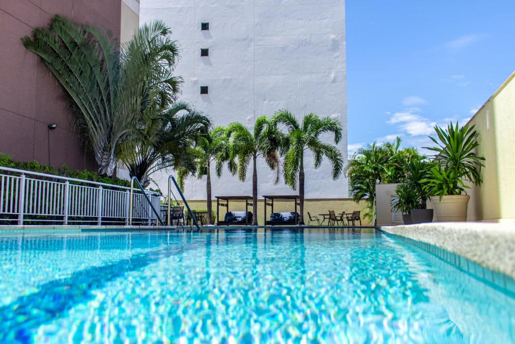 una piscina con palmeras y un edificio en Delmond Hotel, en Cuiabá