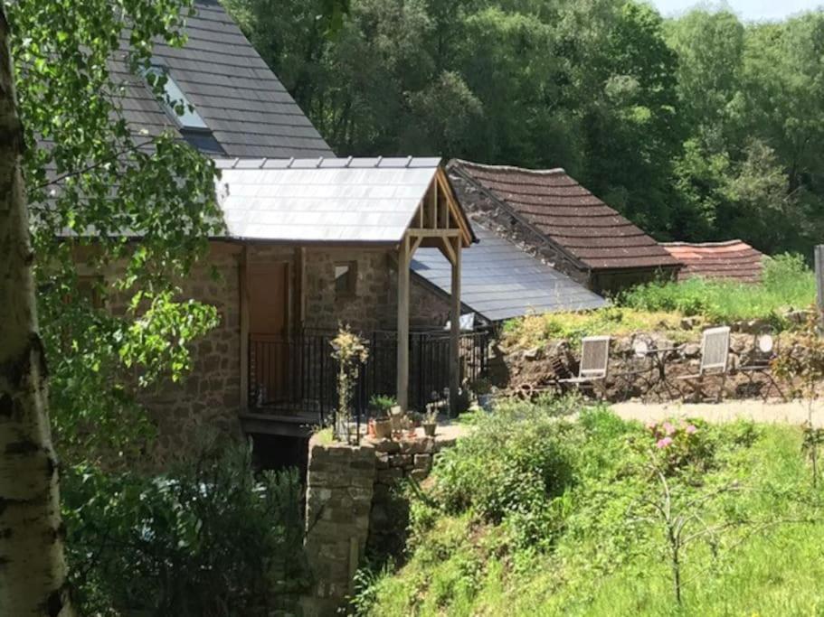 a stone house with a porch on a hill at Woodmill Farm Cottage in Alvington