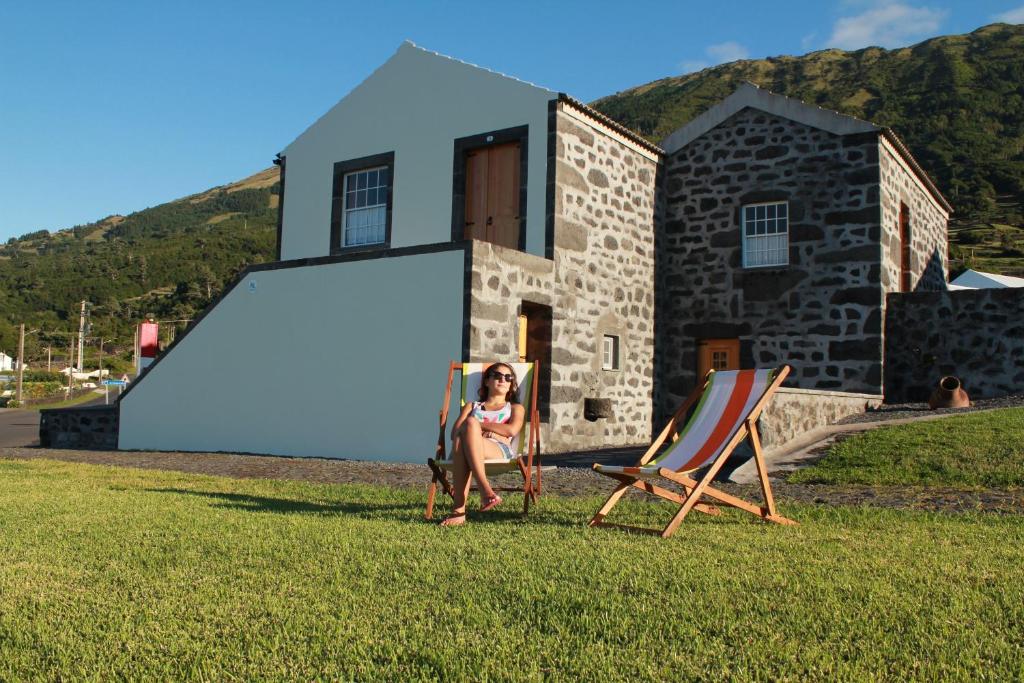 une femme assise sur une chaise devant une maison dans l'établissement A Casa dos Meus Sonhos, à Santo Amaro