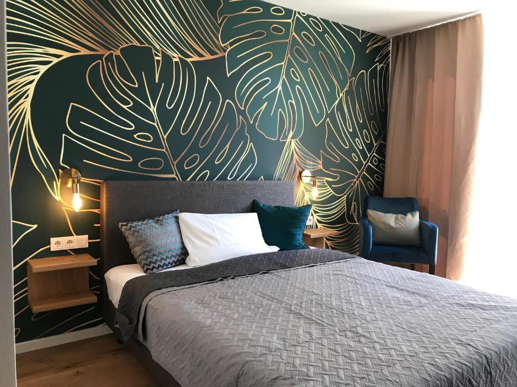 a bedroom with a bed and a wall with leaves at Hotel Hofmeisterhaus - Self Check-in in Massing