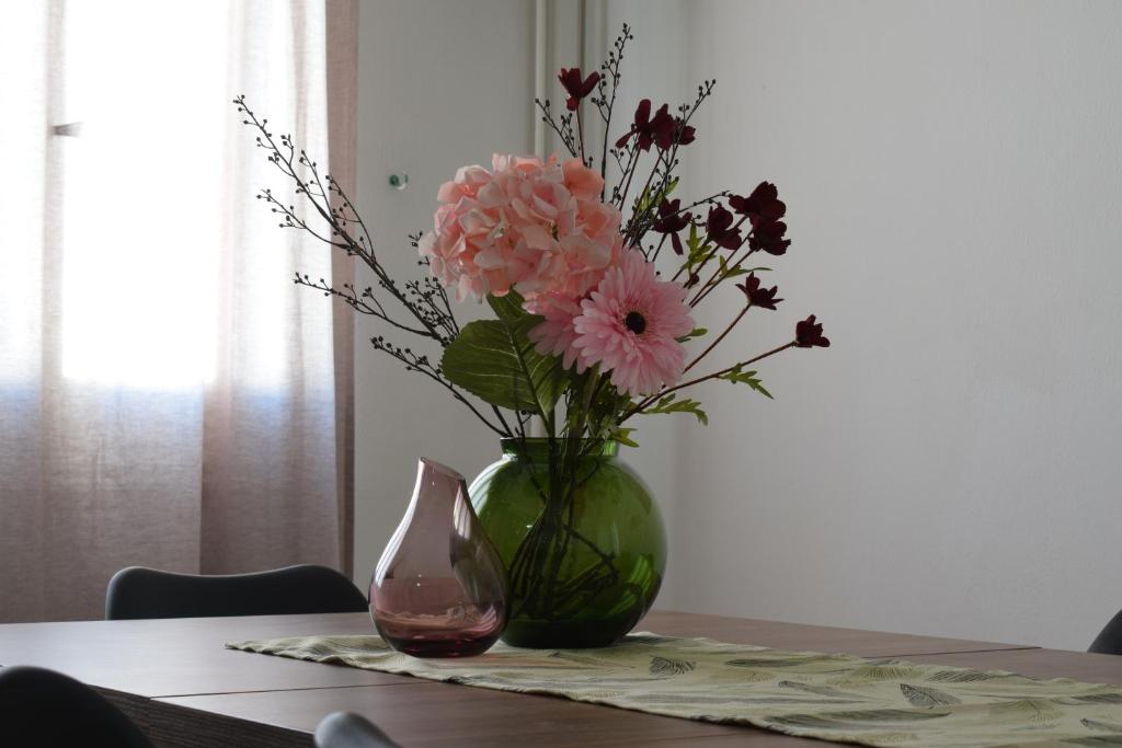 un vase avec des fleurs roses assises sur une table dans l'établissement MAMA'S FLAT - ΤΟ ΔΙΑΜΕΡΙΣΜΑ ΤΗΣ ΜΑΜΑΣ, à Strovolos