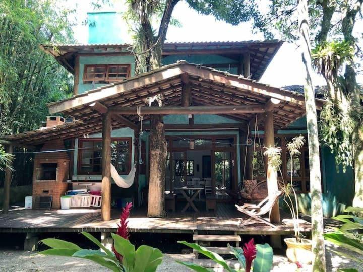 a house with a large wooden deck in a garden at Casa da árvore em Paúba . in São Sebastião