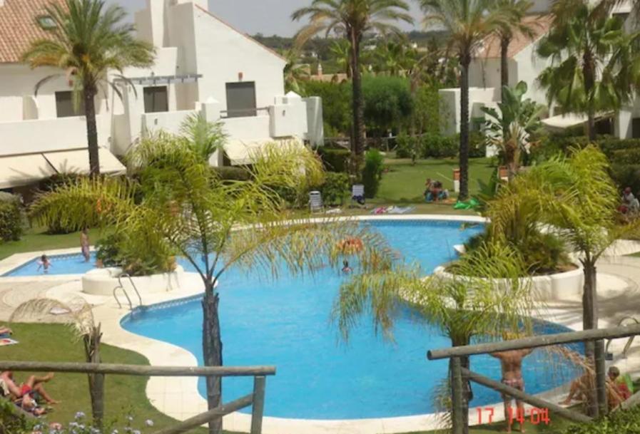 uma grande piscina azul com palmeiras em redor em Islantilla Bajo con Jardin na Islantilla