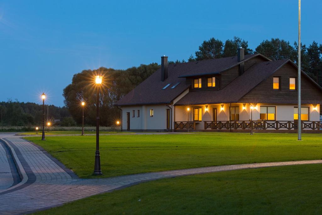 a large house with lights on in the grass at Sodyba Ignė in Druskininkai