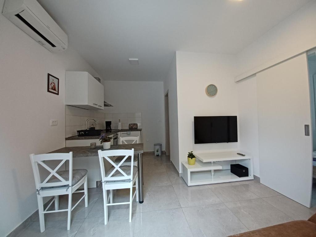 eine Küche und ein Wohnzimmer mit einem Tisch und einem TV in der Unterkunft Apartments LEON 1 in Novigrad Istria