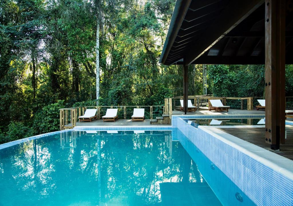 a swimming pool with chairs and trees in the background at Mocona Virgin Lodge in Moconá Falls