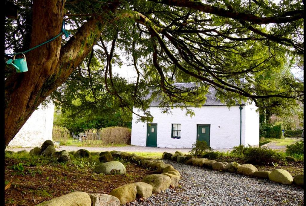 a white building with sheep in front of it at The Bothy of Ballachulish House in Ballachulish