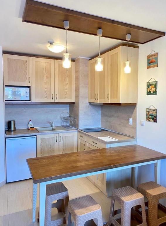 a kitchen with wooden cabinets and a table and stools at Belvedere luxury apartment in Bansko