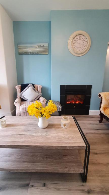 a living room with a table with yellow flowers on it at Beulah Guest House in Portrush