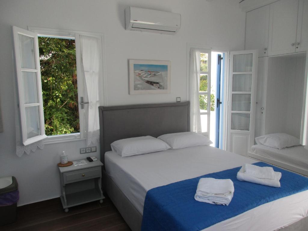 a white bedroom with a bed and two windows at Spetses House - Near Kaiki Beach in Spetses