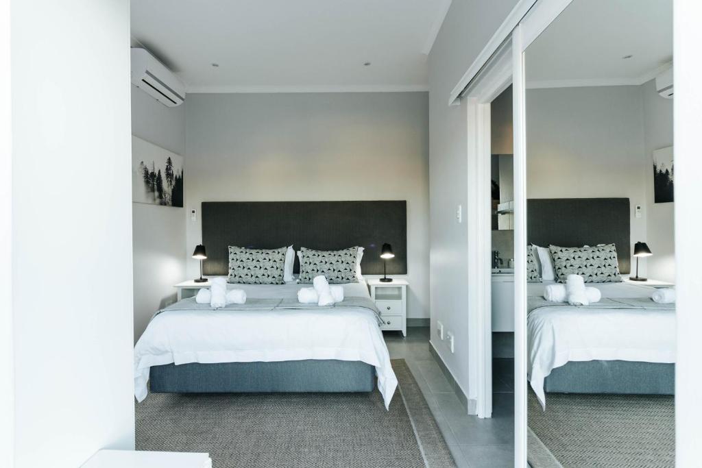 a white bedroom with two beds and a mirror at Kingswood Manor No.17 in George