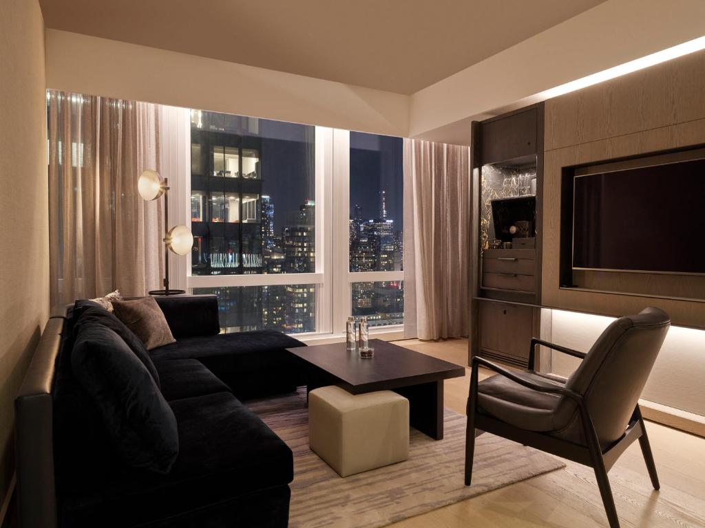 a living room with a couch and a table and a tv at Equinox Hotel Hudson Yards New York City in New York