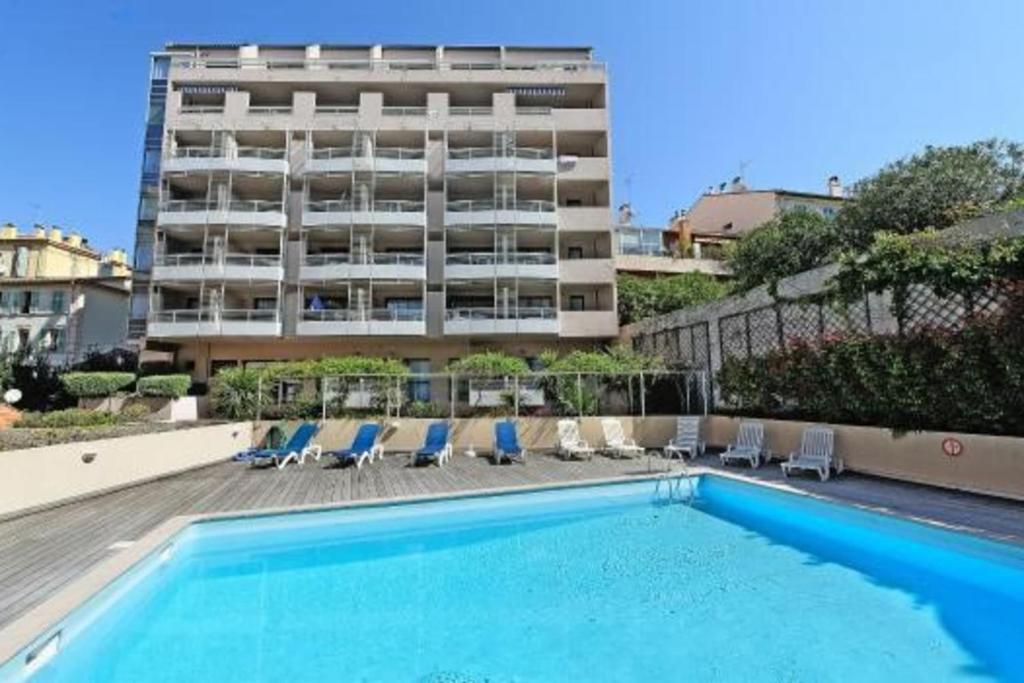 une piscine avec des chaises et un grand bâtiment dans l'établissement Studio At 200m From Beach Residence With Pool, à Cannes
