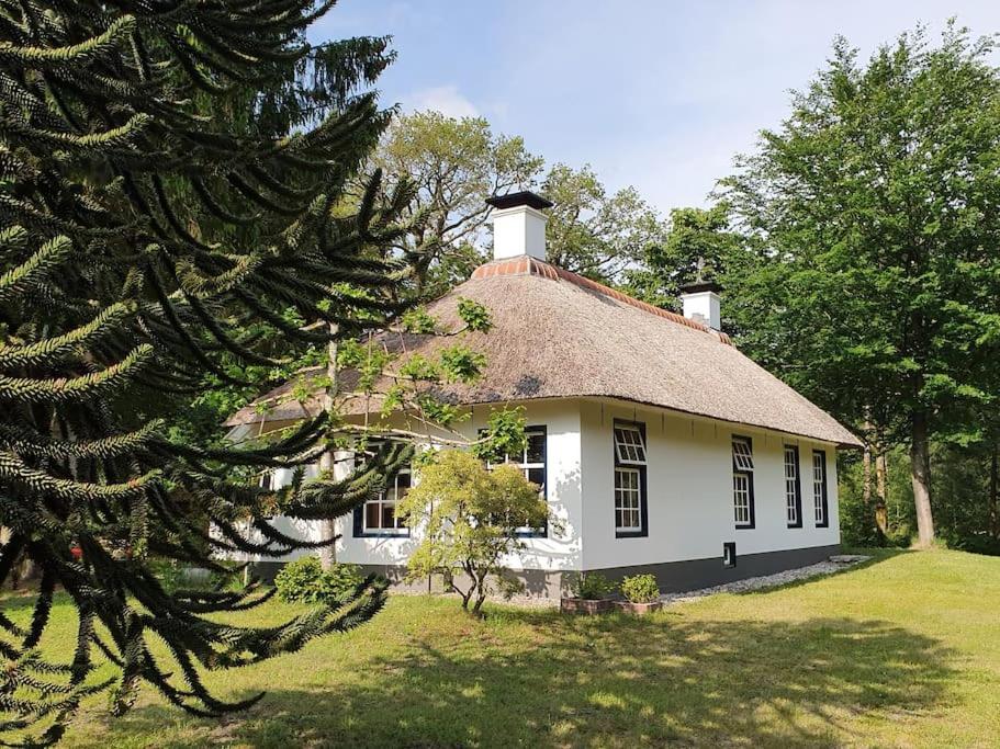 een groot wit huis met een rieten dak bij Midden in de Friese bossen op landgoed Princenhof in Oranjewoud