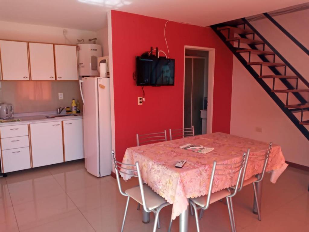 a kitchen with a table and a red wall at Cabaña Amaya in Tandil