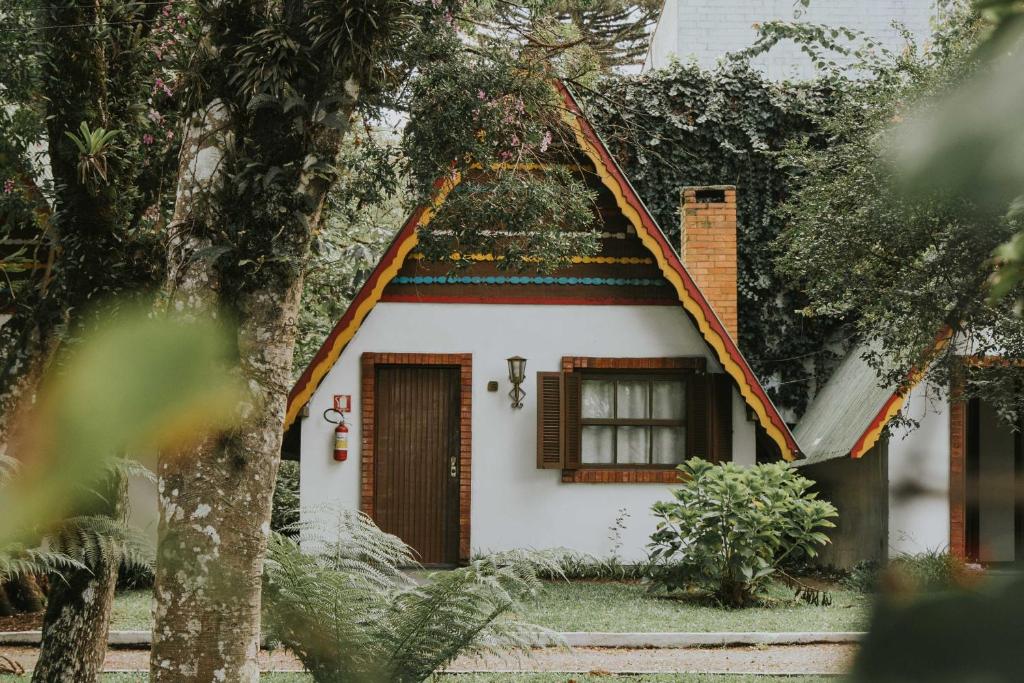 a small white house with a roof at Villa De Chalés Gramado- OH HOTÉIS in Gramado