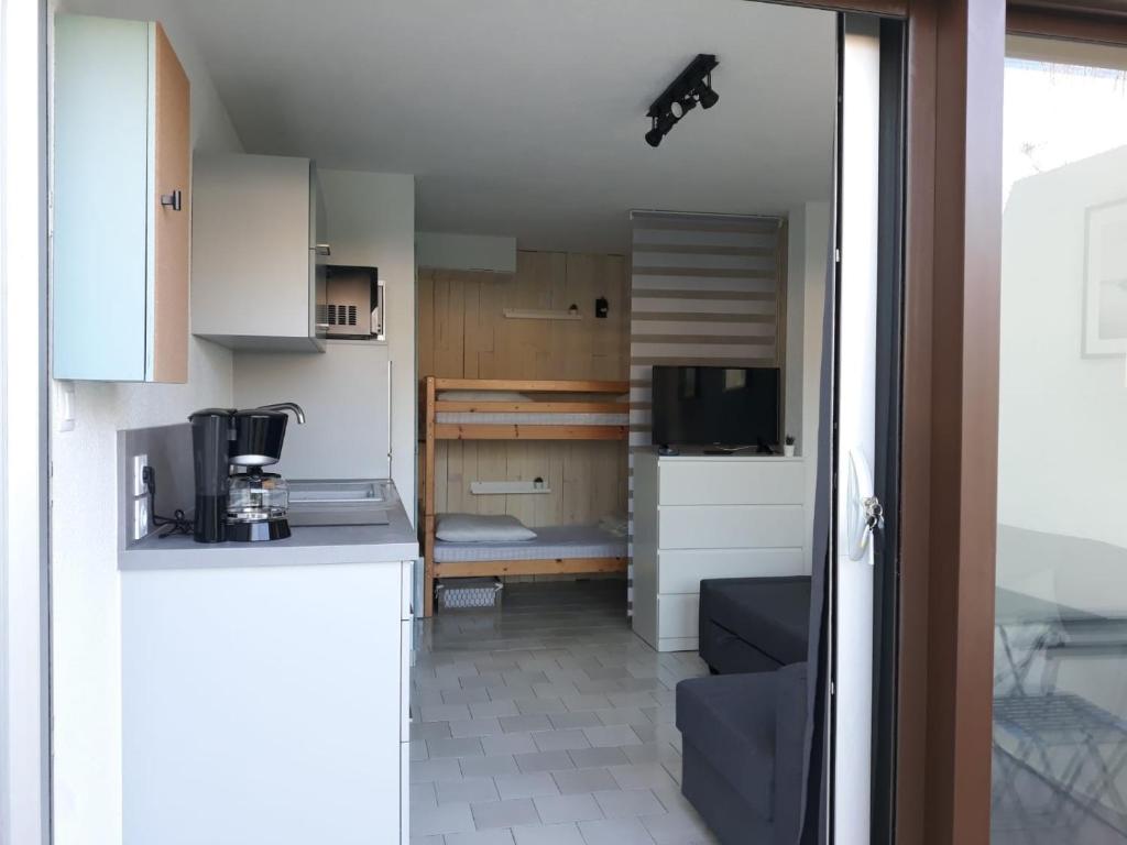 a kitchen with white cabinets and a living room at Studio cabine en bord de plage in Marseillan