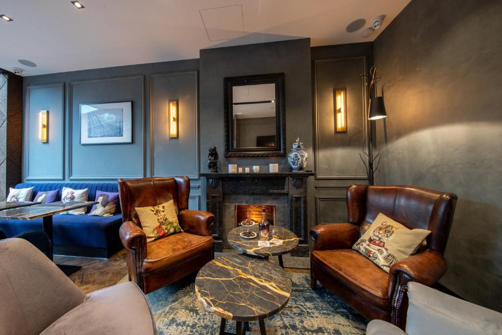 a living room with leather chairs and a fireplace at De Ware Jacob Boutique Hotel in Amsterdam
