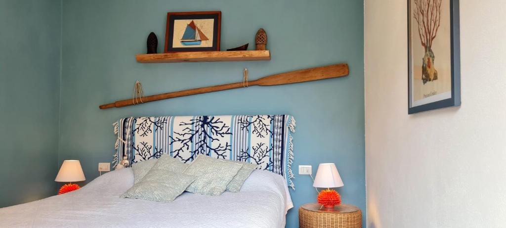 una camera da letto con un letto con pareti blu e due lampade di Residence Cala Francese - Case sul mare a La Maddalena