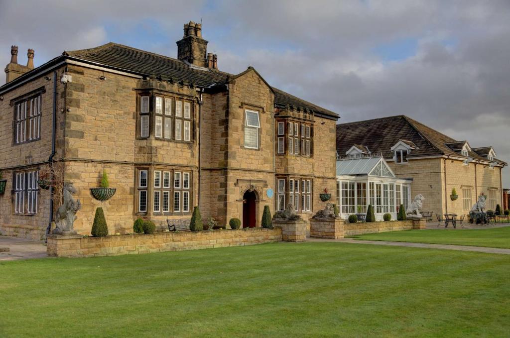 a large brick house with a large grass yard at Rogerthorpe Manor Hotel in Pontefract