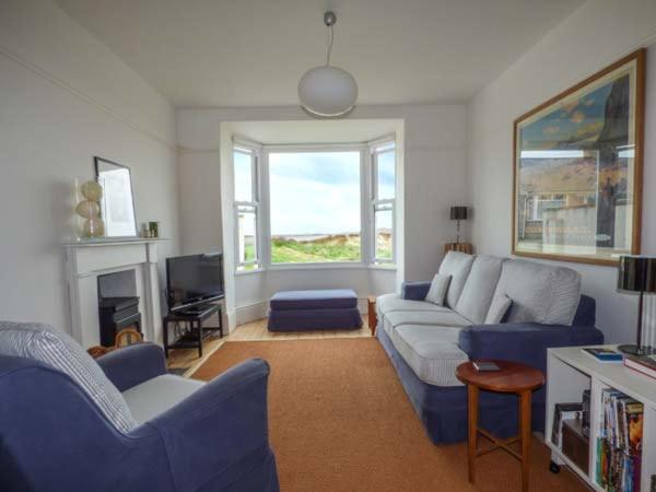 a living room with a couch and chairs and a fireplace at Sandy Bank in Rhosneigr