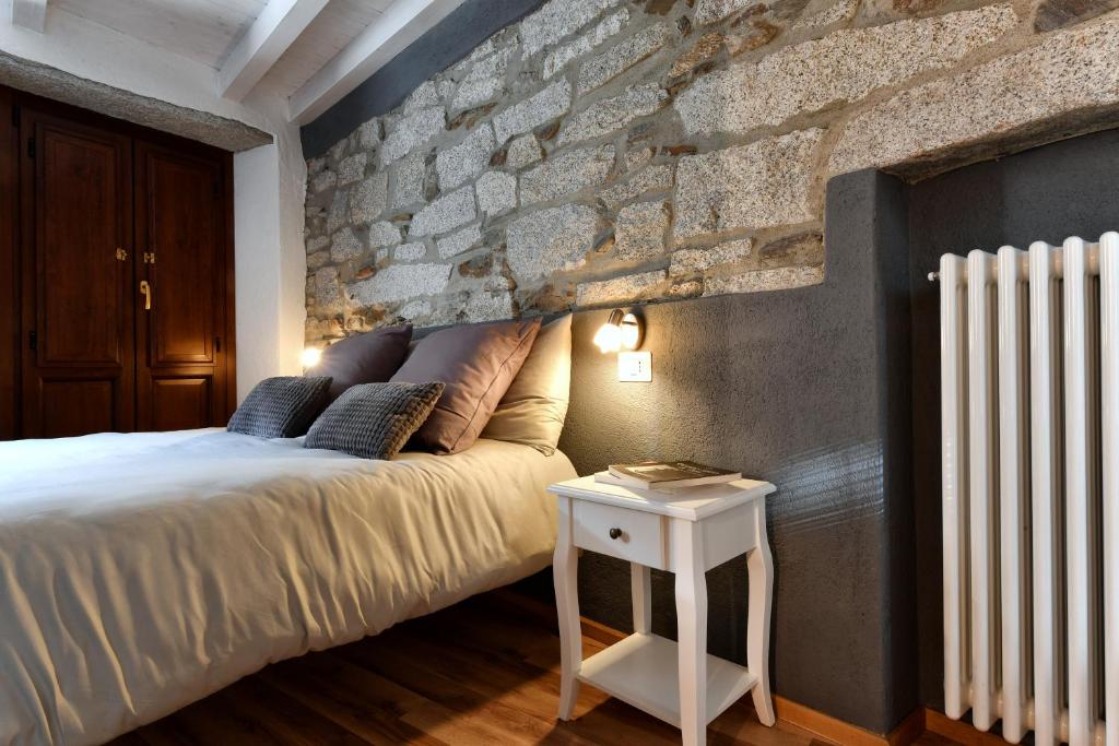 een slaapkamer met een bed en een stenen muur bij Cà Rosa in Mergozzo