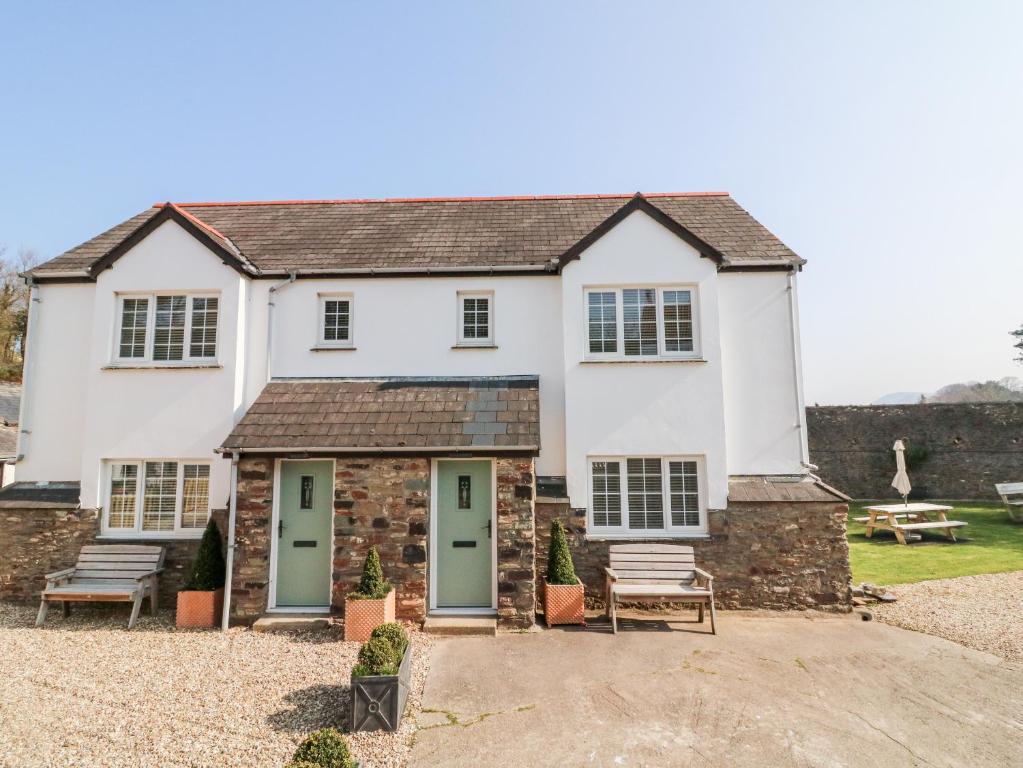 a white house with green doors and benches at Kingfisher Cottage in Ilfracombe